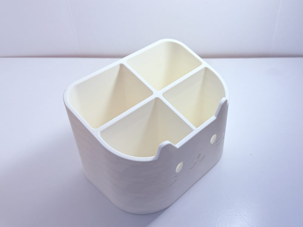 Empty cat-face desk organiser shown from above, showing the four compartments
