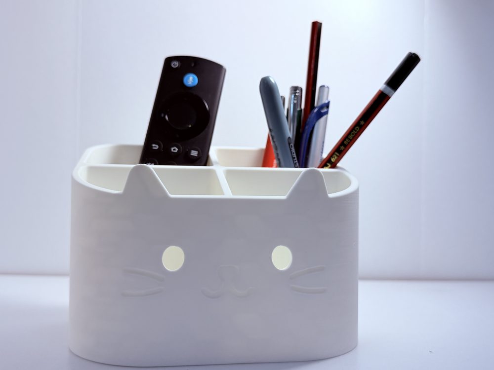 Cat-face desk organiser holding a remote, pens, scissors and nail polish